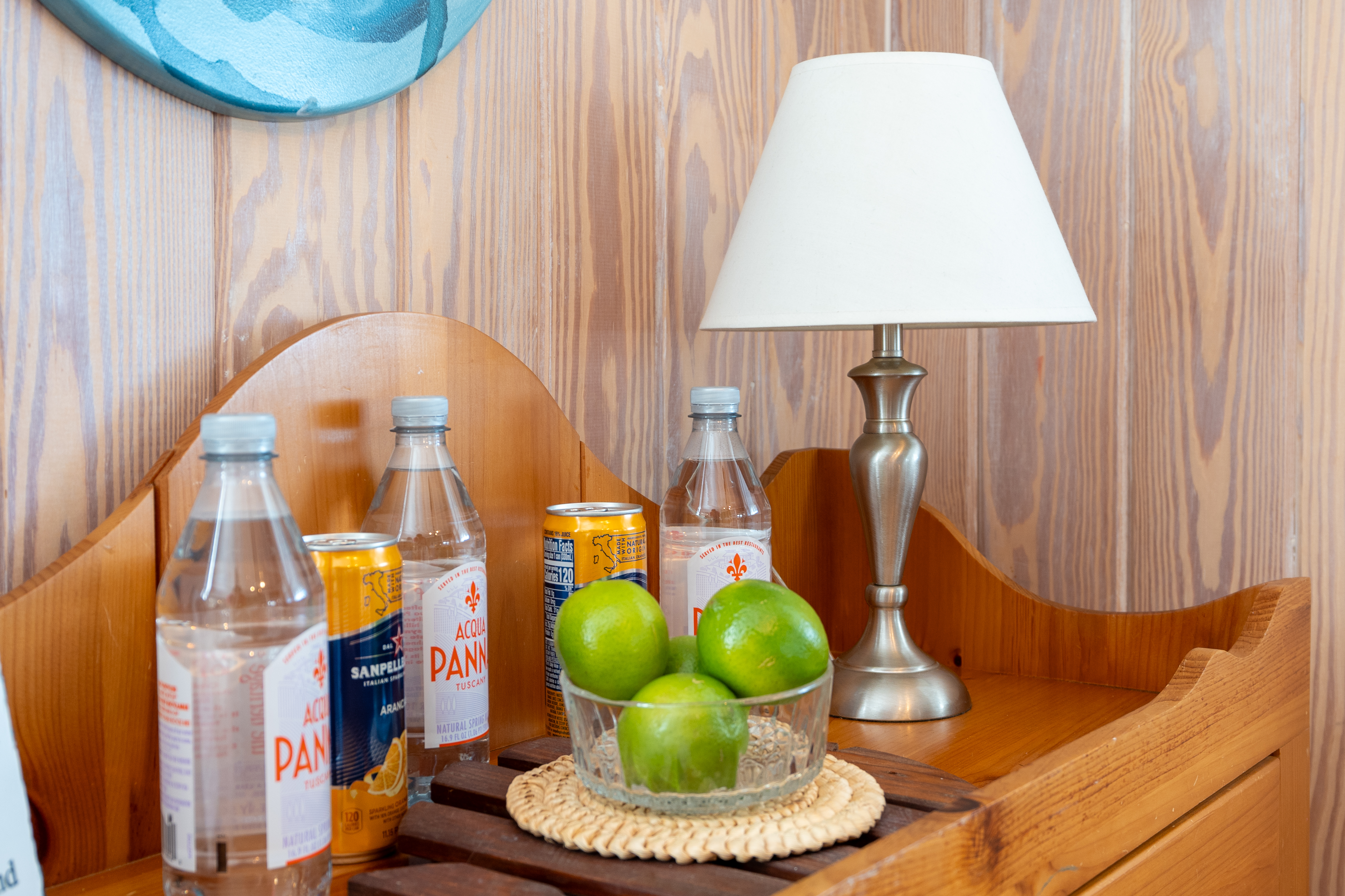 A wooden dresser with a lamp, a bowl of limes and cold drinks
